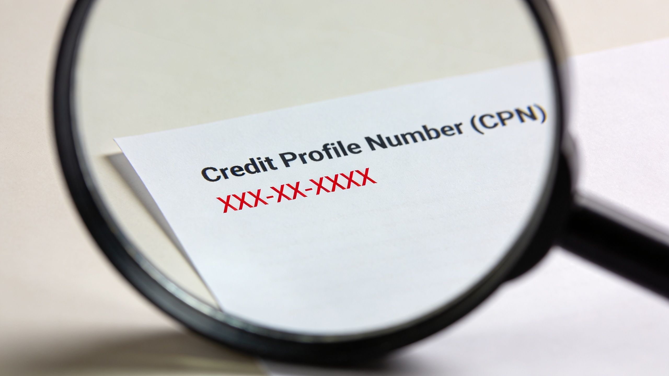 A magnifying glass focusing on a paper displaying the text Credit Profile Number CPN with placeholder digits.